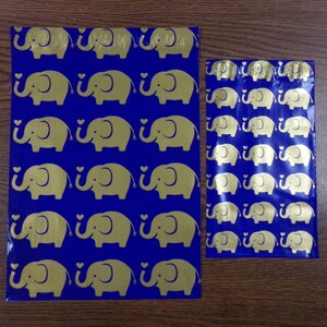 Puede incluir: Dos bolsas de pl&aacute;stico azules con dise&ntilde;os de elefantes dorados. La bolsa m&aacute;s grande mide aproximadamente 25 cm de alto y la m&aacute;s peque&ntilde;a aproximadamente 15 cm de alto.