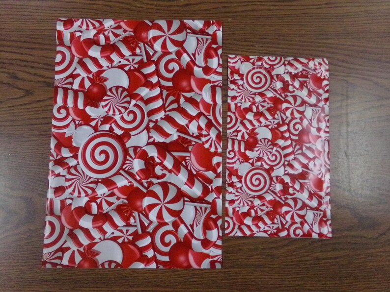 Puede incluir: Dos hojas de papel de regalo rojo y blanco con un patr&oacute;n de bastones de caramelo y menta.