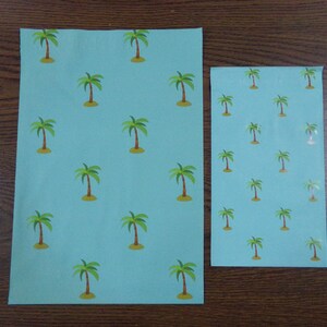 Puede incluir: Dos hojas de papel de regalo azul con un patr&oacute;n repetido de palmeras verdes. La hoja m&aacute;s grande mide 21,6 cm por 27,9 cm, y la hoja m&aacute;s peque&ntilde;a mide 14 cm por 21,6 cm.
