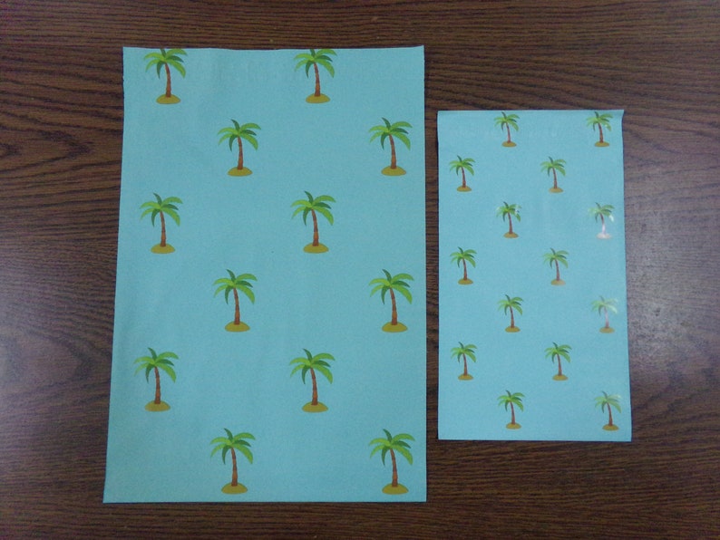 Puede incluir: Dos hojas de papel de regalo azul con un patr&oacute;n repetido de palmeras verdes. La hoja m&aacute;s grande mide 21,6 cm por 27,9 cm, y la hoja m&aacute;s peque&ntilde;a mide 14 cm por 21,6 cm.