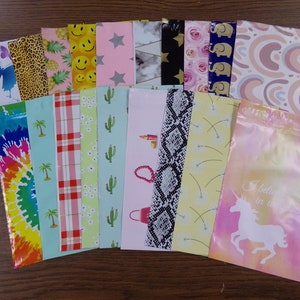 May include: Assortment of 18 colorful patterned plastic resealable bags with zipper closures. The bags feature various designs including pineapples, smiley faces, stars, marble, cacti, palm trees, plaid, snakeskin, dandelions, rainbows, and a unicorn with the text "I believe in the magic".