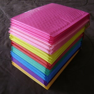 Puede incluir: Una pila de sobres de burbujas de colores en varios tonos de rosa, amarillo, naranja, verde, azul y morado.