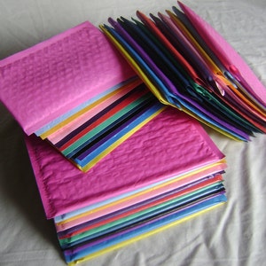 May include: A stack of colorful bubble mailers, with a pink mailer on top. The mailers are made of a textured, bubble-wrapped material.