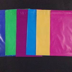 May include: Six colorful plastic mailing envelopes in blue, green, purple, light blue, yellow, and pink.