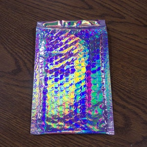 May include: A silver iridescent bubble mailer with a pattern of small circles. The mailer is sealed on three sides.