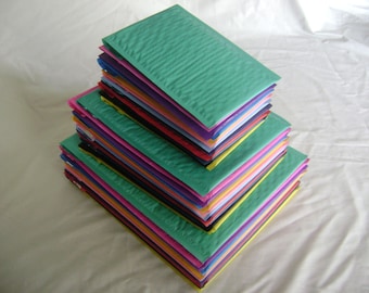 May include: A stack of colorful bubble mailers in various shades of green, pink, yellow, orange, blue, purple, and black.