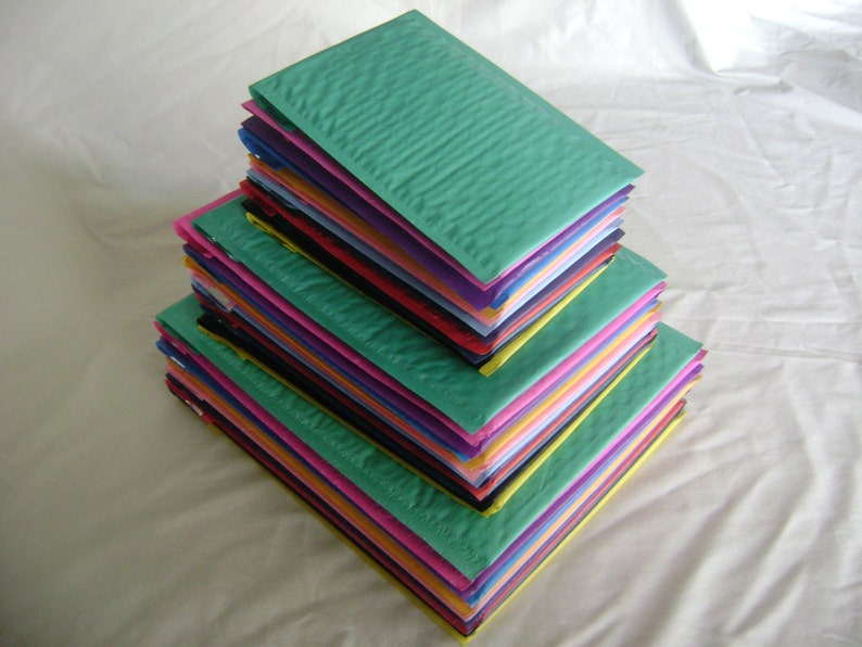 May include: A stack of colorful bubble mailers in various shades of green, pink, yellow, orange, blue, purple, and black.