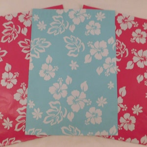 May include: Three sheets of wrapping paper with a tropical floral pattern. The paper is pink and blue with white hibiscus flowers and leaves.