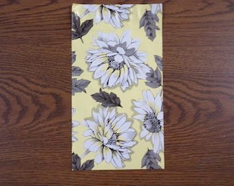 May include: A yellow background with a repeating pattern of white flowers with gray centers and gray leaves.