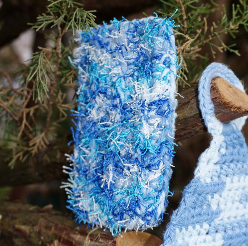 May include: A blue and white crocheted scarf with a fluffy texture. The scarf is made with a variety of shades of blue and white yarn.