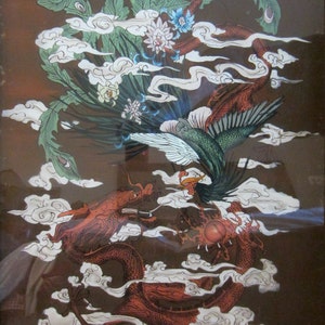 May include: A framed print featuring a detailed illustration of a red dragon and a green phoenix intertwined amidst white stylized clouds. The dragon is positioned at the bottom, while the phoenix soars above, surrounded by floral accents.