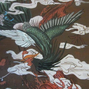 May include: A detailed illustration featuring a green and white phoenix in flight amidst stylized white clouds on a brown background. A red dragon with a scaly body is partially visible at the bottom, alongside white floral elements.