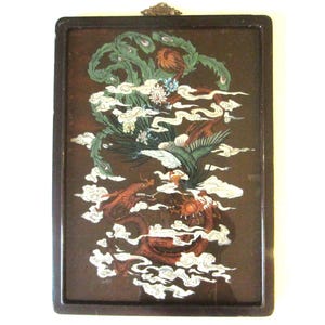 May include: A rectangular wall hanging featuring a dark brown frame and a central illustration of a green phoenix and a red dragon intertwined among white clouds. The artwork includes floral accents and a small decorative metal hanger at the top.