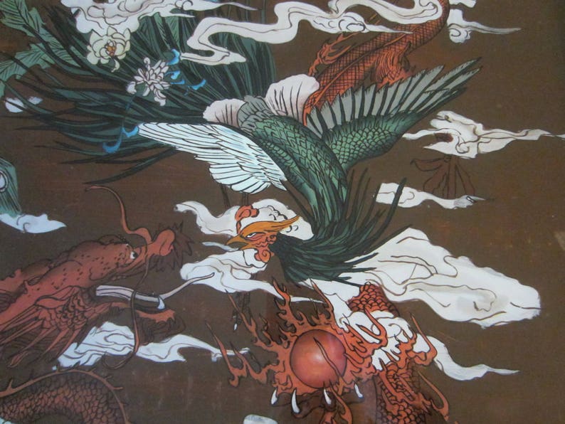 May include: A detailed illustration on a brown background featuring a green and white phoenix with long tail feathers flying above a red dragon. The dragon has a long body and scales, and both creatures are surrounded by stylized white clouds.