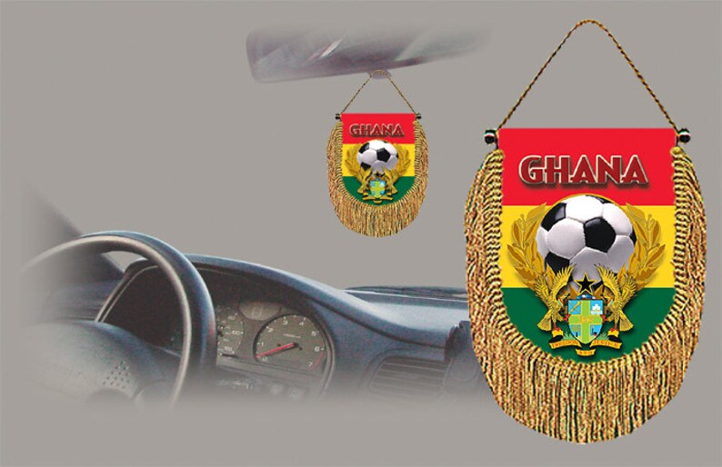May include: A red, yellow, and green car hanging flag with a soccer ball and the word "GHANA" in white letters. The flag has gold fringe and is attached to a string.
