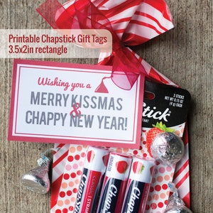 May include: A printable gift tag with the text "Wishing you a Merry Kissmas & Chappy New Year!"  The tag is red with white polka dots and is tied with a red ribbon to a clear plastic bag filled with three red and white ChapStick lip balms and silver Hershey's Kisses.