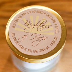 May include: A gold lid with a white label that reads "PRESS FORWARD WITH A STEADFASINESS IN CHRIST HAVING A PERFECT... JHUS SAITH THE FATHER: YE SHALL HAVE ETERNAL LIFE 2 NEPH 3:20" and the words "Brightness of Hope" in a decorative font.