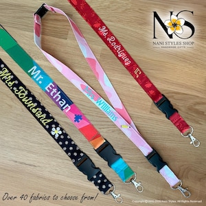 May include: A collection of colorful lanyards with various patterns and personalized text. The lanyards feature names like "Mr. Ethan" and "Ms. Rodriguez." The image also includes the text "Over 40 fabrics to choose from!" and a logo.