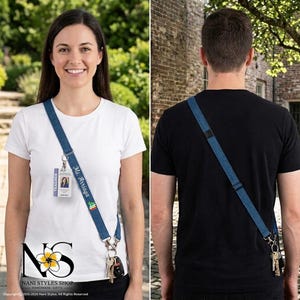 May include: A blue denim crossbody lanyard strap featuring an adjustable buckle, silver-toned metal swivel clasps, and a personalized name embroidery. The strap is attached to a clear plastic ID badge holder and a set of metal keys.