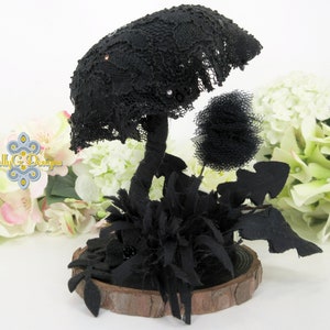 May include: Black lace mushroom with a black tulle puff ball and black fabric leaves on a wooden base.