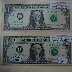 May include: Two 1955 one-dollar Federal Reserve star notes from Minneapolis, each encased in a clear protective sleeve. The bills feature George Washington, green Treasury seals, and serial numbers I10841187 and I10841186 with star suffixes.