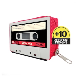 Può includere: Un astuccio rosso con cerniera a forma di musicassetta vintage. L'astuccio presenta un design a cassetta bianco e nero con la scritta "SETE MUSIC 90" e "MDC". L'astuccio ha una cerniera argentata e un adesivo "+10 DIFFERENT DESIGNS".