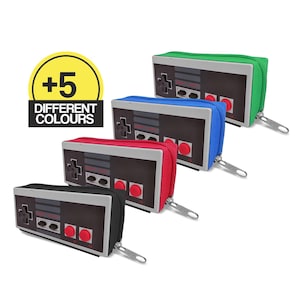 May include: A collection of pencil cases designed to resemble a classic video game controller. The cases are available in black, red, blue, green, and other colors. Each case features a zipper closure and a detailed controller design.