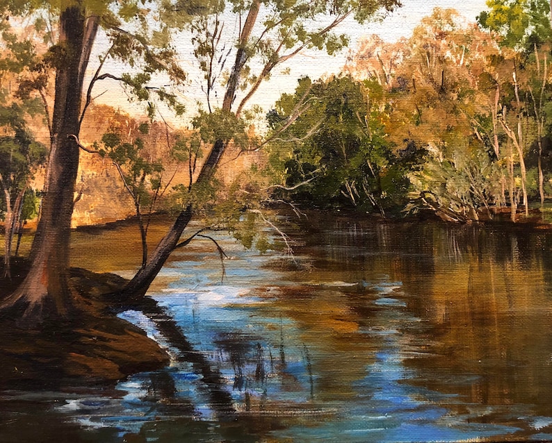 Pu&ograve; includere: Dipinto a olio di una serena scena fluviale. L'acqua riflette gli alberi e il cielo, creando un effetto specchio. L'opera utilizza verdi, marroni e blu, con la luce del sole che filtra attraverso gli alberi, creando un'atmosfera pacifica.