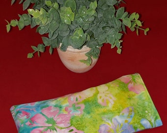 May include: A rectangular fabric pouch featuring a watercolor-style print with vibrant pink flowers, green foliage, and blue accents on a light background. The pouch has visible stitching along the edges and a flat, elongated rectangular shape.