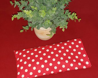 May include: A rectangular fabric pouch featuring a vibrant red background with a repeating pattern of small white polka dots. The pouch is stitched along the edges and lies flat, showcasing a clean, simple design with a consistent dot distribution.