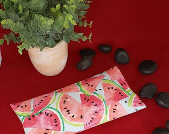 May include: A rectangular fabric pouch featuring a watercolor-style print of pink watermelon slices with black seeds on a light blue background. The pouch is flat and has a stitched edge, displaying a vibrant fruit-themed pattern throughout.