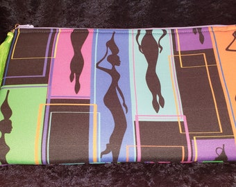 May include: A rectangular zippered pouch featuring a vibrant print of black silhouettes of figures carrying vessels on their heads. The design includes vertical panels in shades of green, pink, purple, blue, and orange, accented by a bright lime green tassel.