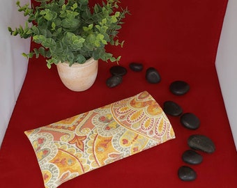 May include: A rectangular fabric pouch featuring a vibrant paisley pattern in shades of orange, yellow, and muted green. The textile design consists of intricate swirling motifs and floral shapes arranged in a repeating, symmetrical layout.