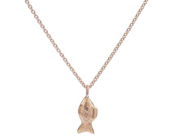 May include: A rose gold necklace featuring a fish pendant. The pendant has a textured surface and is suspended from a delicate chain. The necklace is a simple, elegant piece of jewelry.