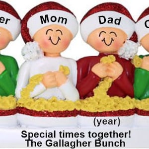 May include: A family Christmas ornament featuring four figures wearing Santa hats. Each figure has a name on their hat: Roger, Mom, Dad, and Cissy. The ornament has the text "Special times together! The Gallagher Bunch".