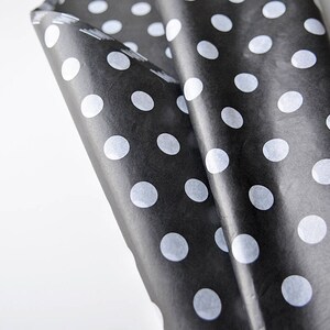 May include: Black and white polka dot wrapping paper. The paper is folded and the white polka dots are visible on the black background.