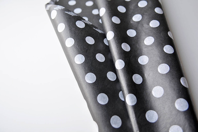 May include: Black and white polka dot wrapping paper. The paper is folded and the white polka dots are visible on the black background.