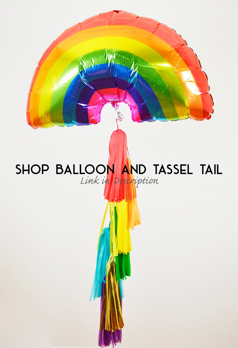 Puede incluir: Globo de aluminio en forma de arco&iacute;ris con una cola de borla. El globo tiene forma de arco&iacute;ris y un acabado brillante. La cola de borla est&aacute; hecha de papel de seda de colores y est&aacute; unida a la parte inferior del globo.