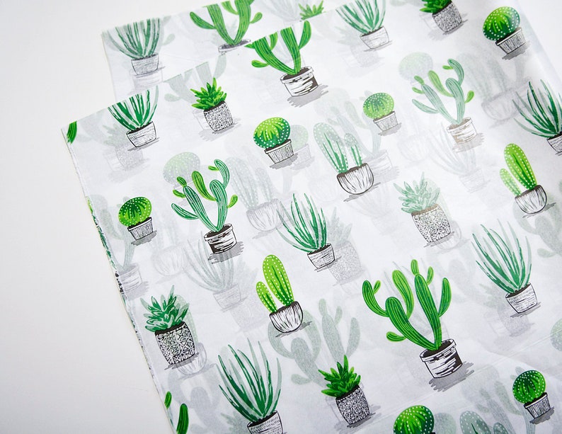 K&ouml;nnte beinhalten: Wei&szlig;es Geschenkpapier mit einem sich wiederholenden Muster aus gr&uuml;nen Kakteen in verschiedenen Stilen und Gr&ouml;&szlig;en. Die Kakteen befinden sich in wei&szlig;en T&ouml;pfen.