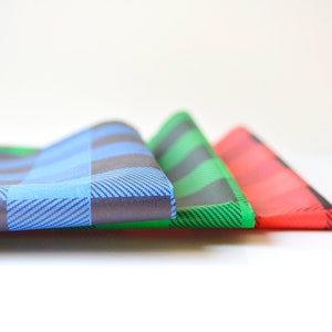 May include: Three folded fabric squares in blue, green, and red plaid patterns.