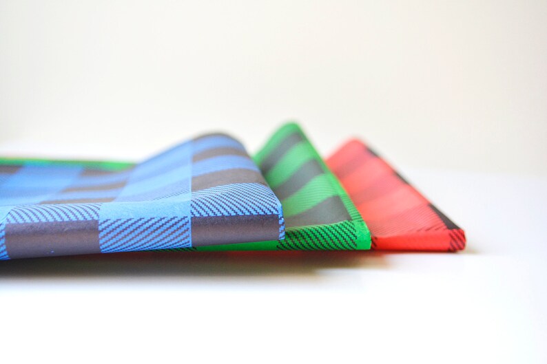 May include: Three folded fabric squares in blue, green, and red plaid patterns.