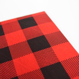 May include: Red and black buffalo plaid fabric with a textured surface.