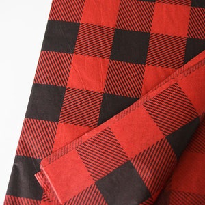 May include: Red and black buffalo plaid tissue paper. The paper is folded in half and the pattern is visible on both sides.