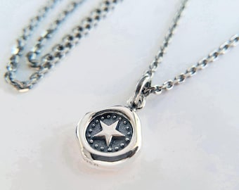 May include: A silver necklace with a silver pendant featuring a star design. The pendant is round and has a textured surface. The chain is a curb chain.
