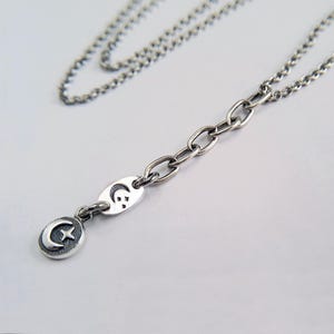 May include: A silver chain necklace with a crescent moon and star charm. The chain is made of small, linked circles.