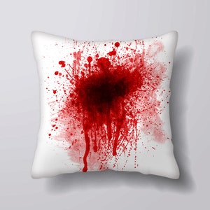 May include: White cushion with a large red blood splatter design.