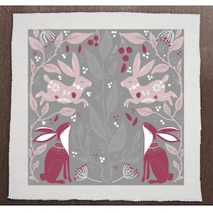 May include: A grey and pink fabric with a repeating pattern of stylised hares and floral designs. The hares are in a leaping pose and a sitting pose. The floral designs include leaves, berries, and flowers.