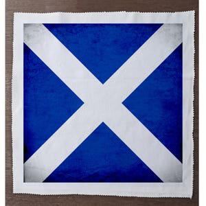 May include: A blue and white fabric square with a white cross on a blue background. The fabric has a distressed, vintage look.
