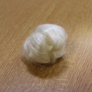May include: A close-up of a white, fluffy ball of silk fibers. The silk is soft and delicate, and it is perfect for crafting or making yarn.