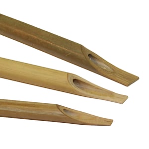 Peut inclure: Trois stylos de calligraphie en bambou sont présentés sur fond blanc. Les stylos, de tons bruns et beiges, ont une pointe creuse pour l'encre. Les pointes sont coupées en biais. Les stylos sont disposés à différentes profondeurs.
